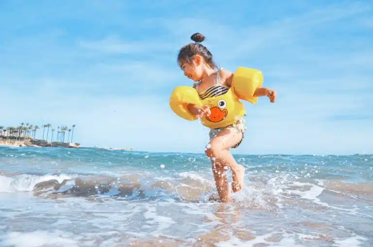 girl playing in water while wearing a puddle jumper which is considered by some to be dangerous