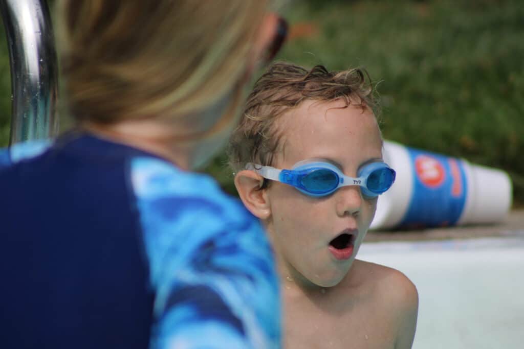 child learning to blow nose and taking big breath during swim lessons