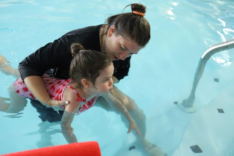 swim instructor teaching student to hold breath while swimming using chipmunk cheeks